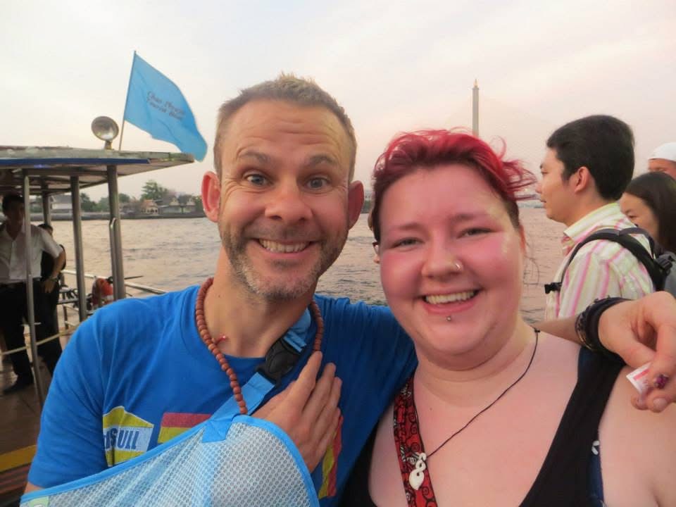 A picture of a younger Ellie with bright red hair smiling next to Dominic Monaghan, who has his right arm in a sling against his chest. 